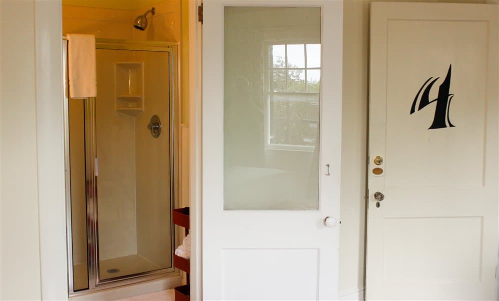 A bathroom featuring a glass shower and two doors, one of which is partially translucent.