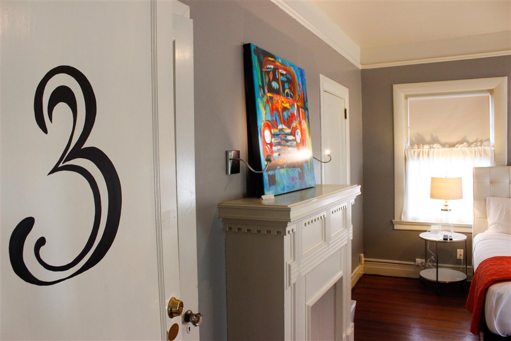 A cozy room featuring a fireplace, colorful artwork, and door number three.