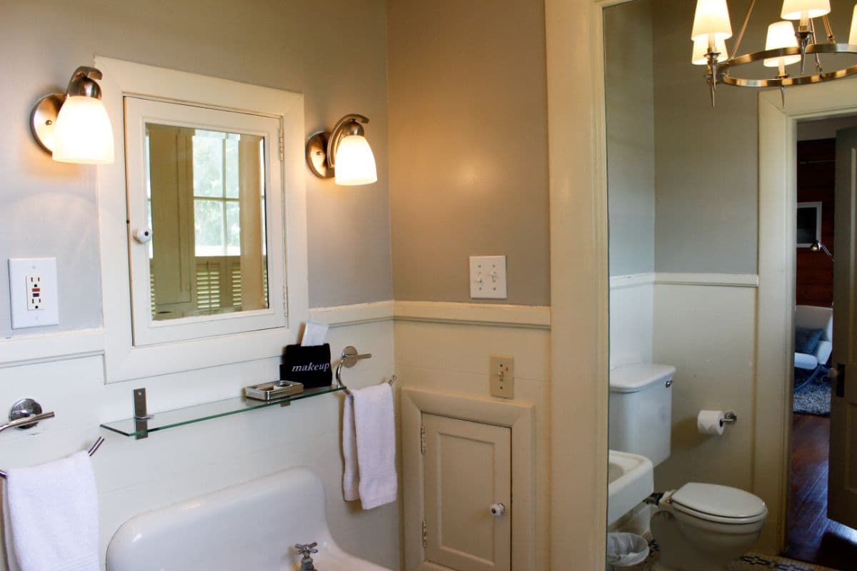 A modern bathroom featuring a sink, cabinet, mirror, and toilet with soft lighting.