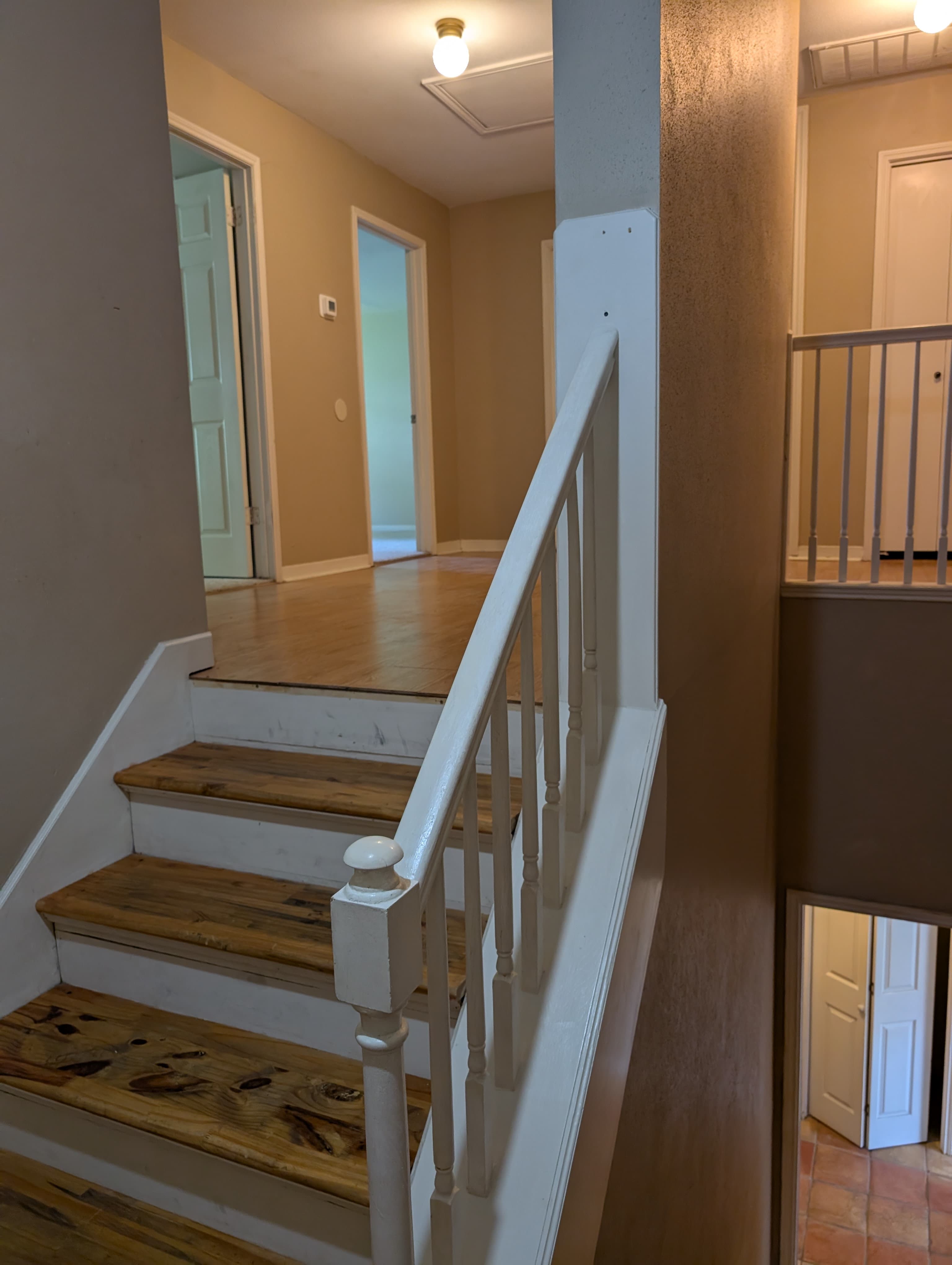 A view of a staircase leading to an upper level with light-colored walls and doors in the hallway.
