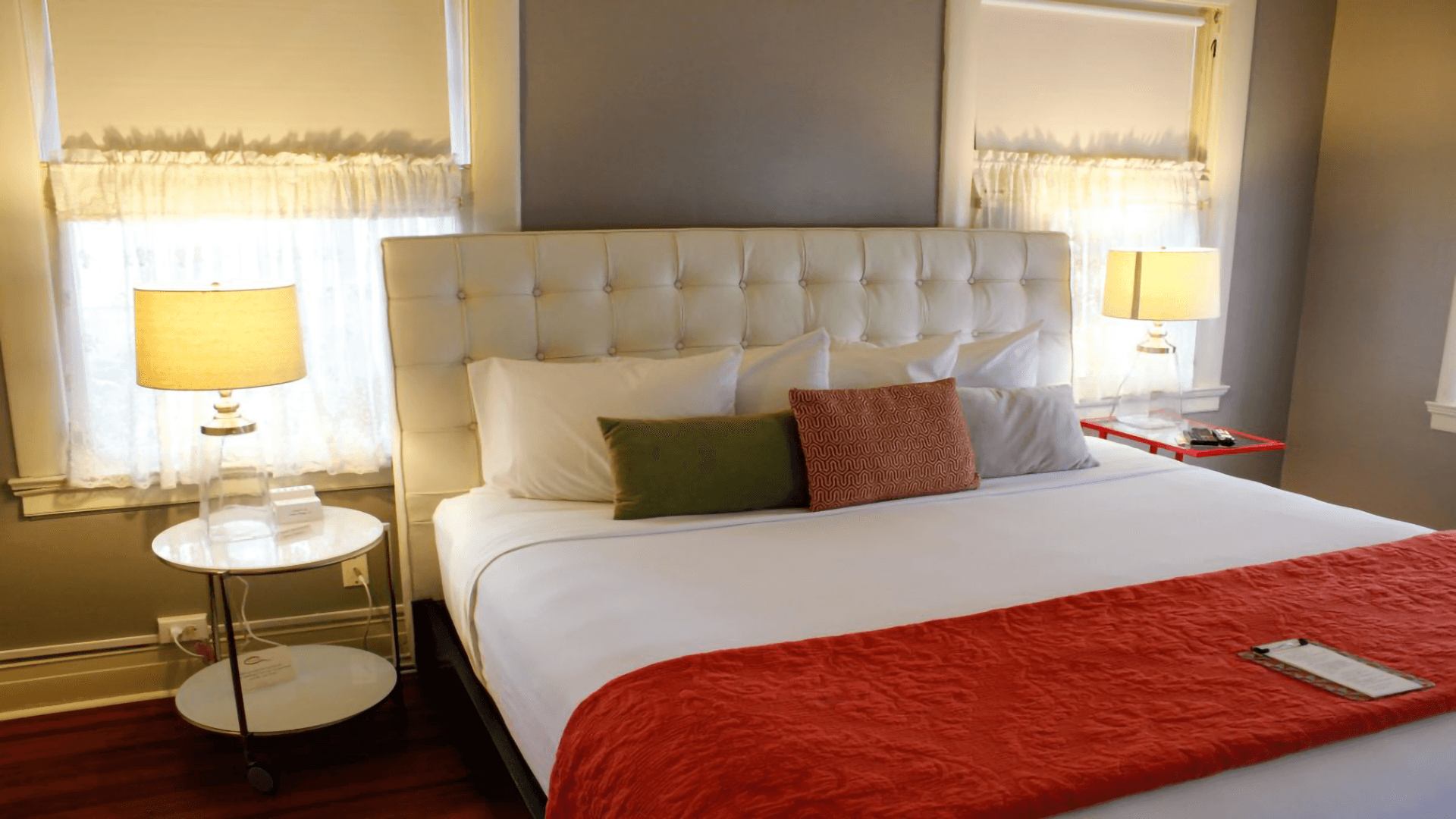 A cozy bedroom featuring a white tufted headboard, colorful pillows, and soft lighting from bedside lamps.