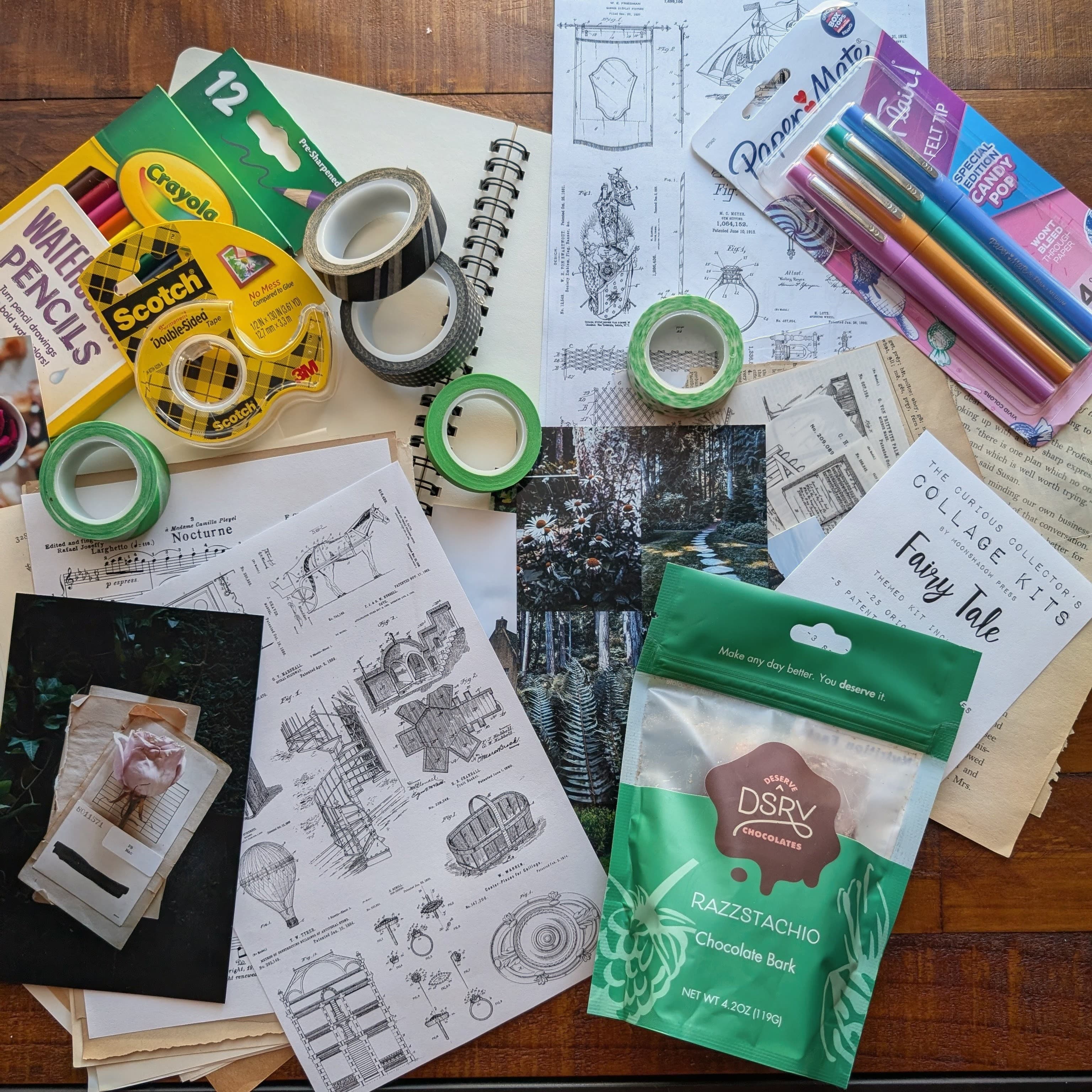 A creative workspace filled with art supplies, papers, and a pack of chocolate bark.