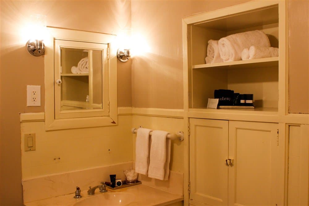 A simple bathroom with a sink, neatly arranged towels, and soft lighting.