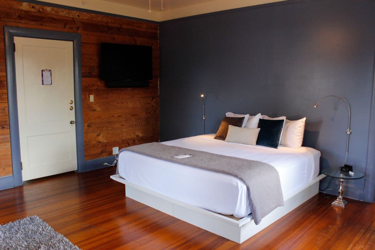 A modern bedroom with a queen-sized bed, wooden accents, and a flat-screen TV.