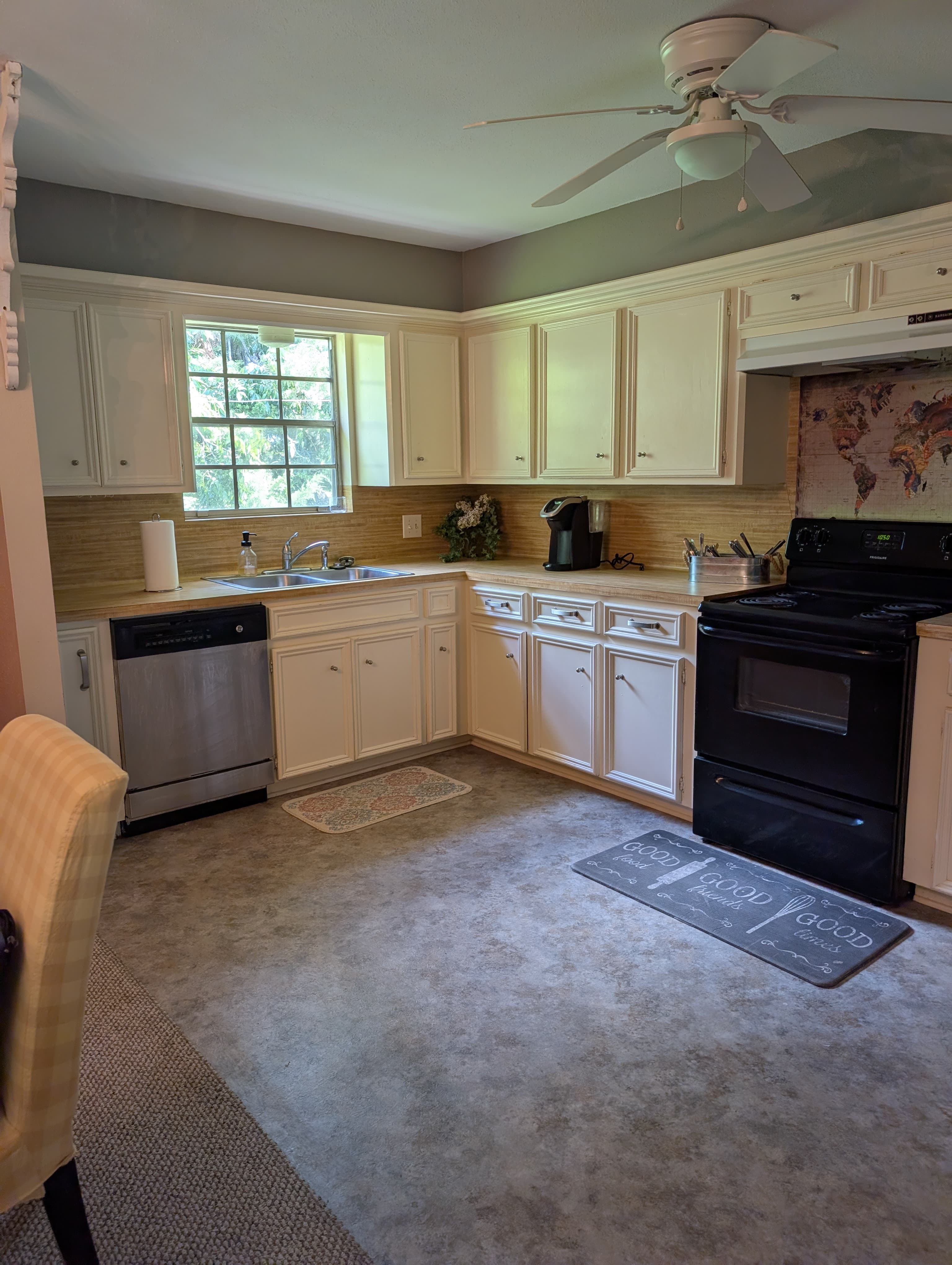 Bright kitchen with white cabinets, a window, and stainless steel appliances.