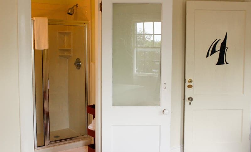 A bathroom with a glass shower stall and two doors, one featuring a number "4".