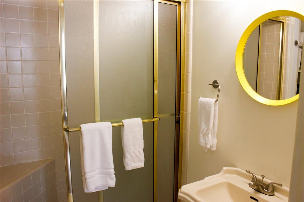 A bathroom featuring a glass shower enclosure, a sink, and neatly hung white towels.
