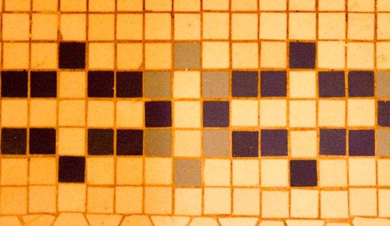 A patterned mosaic floor featuring a mix of black, blue, grey, and white tiles.