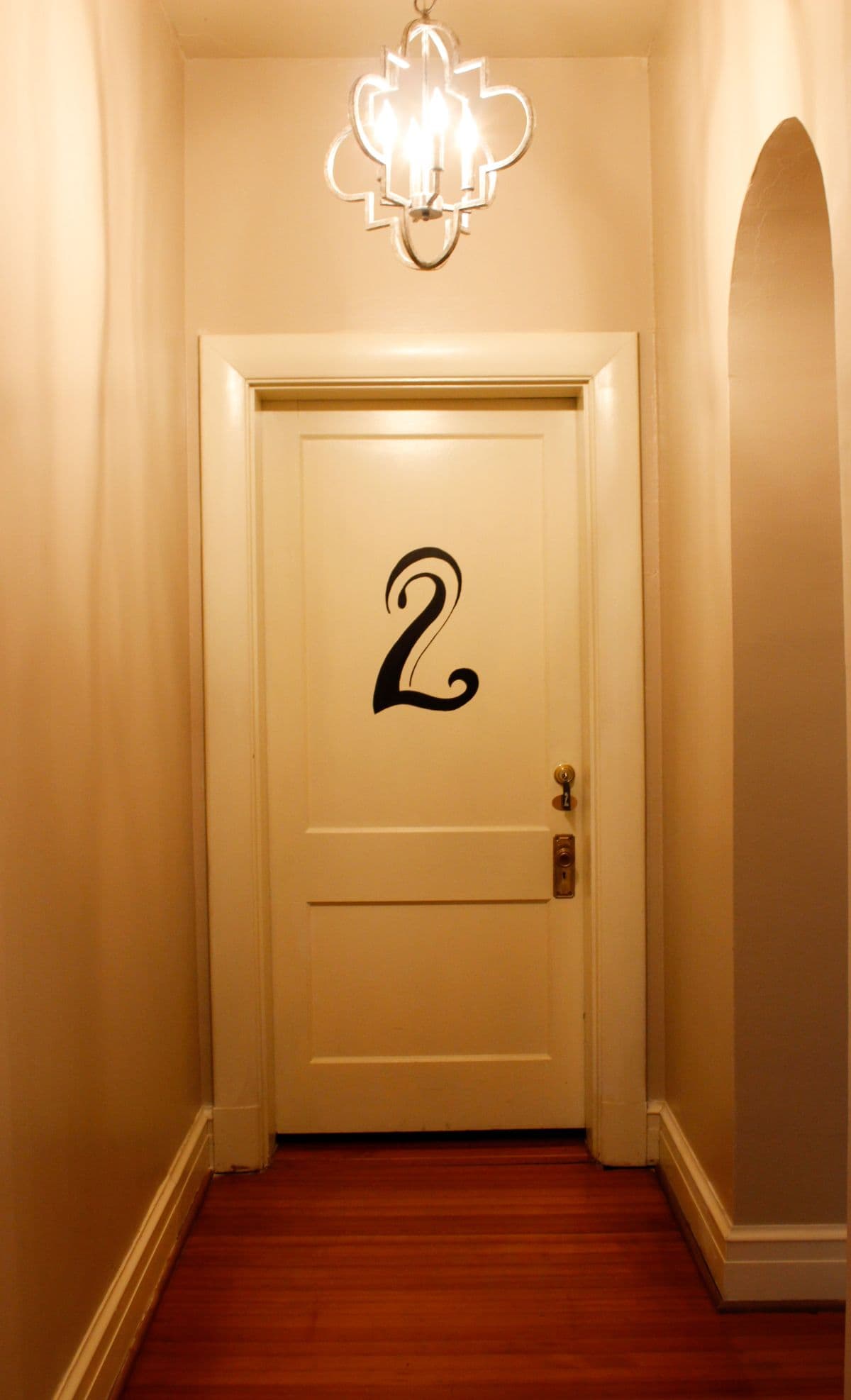 A white door with the number "2" displayed prominently, set in a hallway with warm lighting.