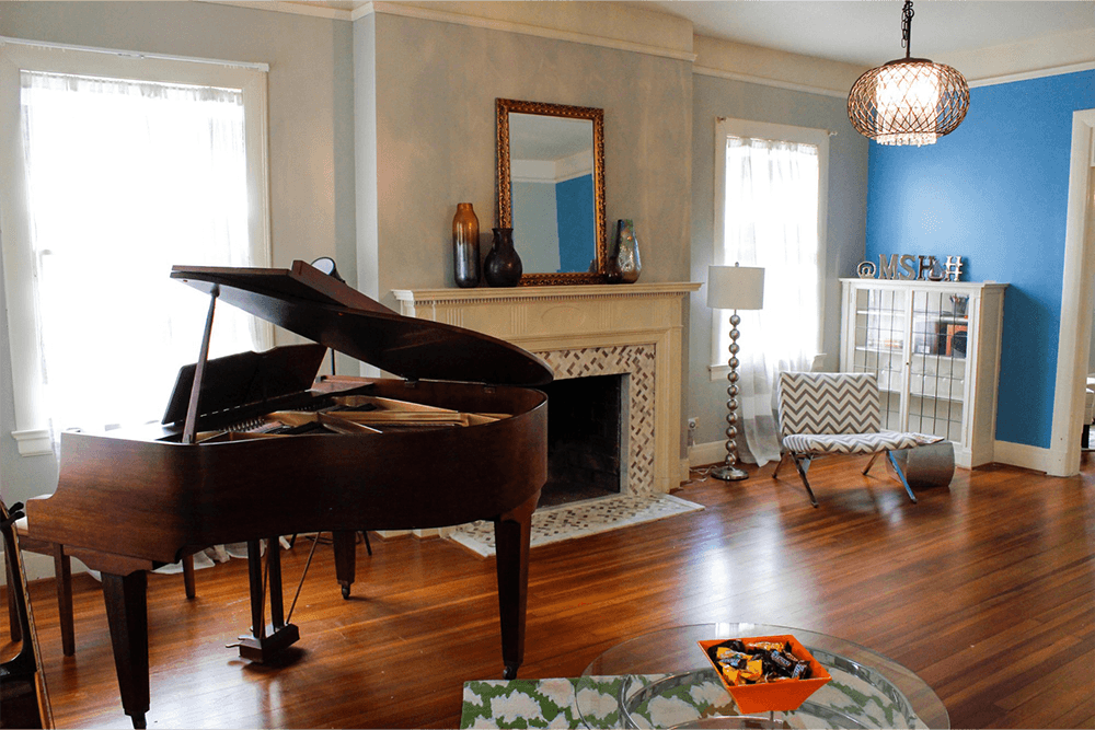 A cozy living room featuring a grand piano, fireplace, and modern decor.