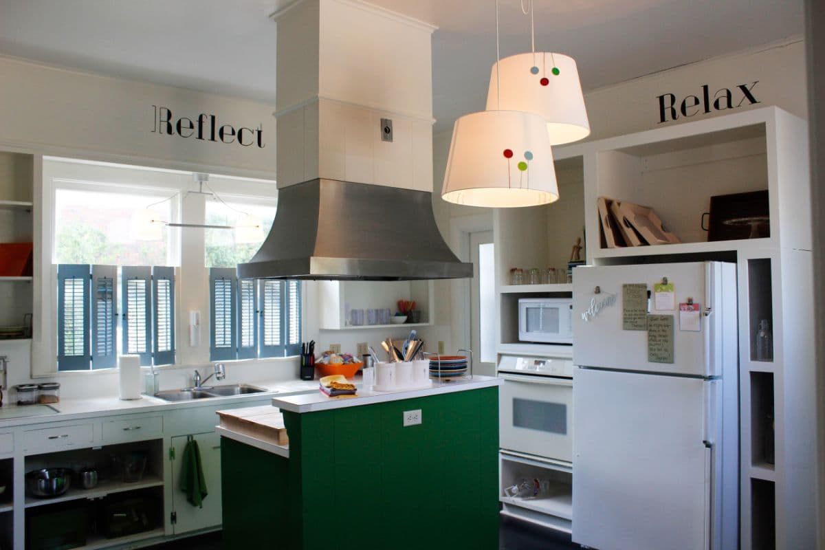 A modern kitchen featuring green accents, stainless steel appliances, and decorative lighting.