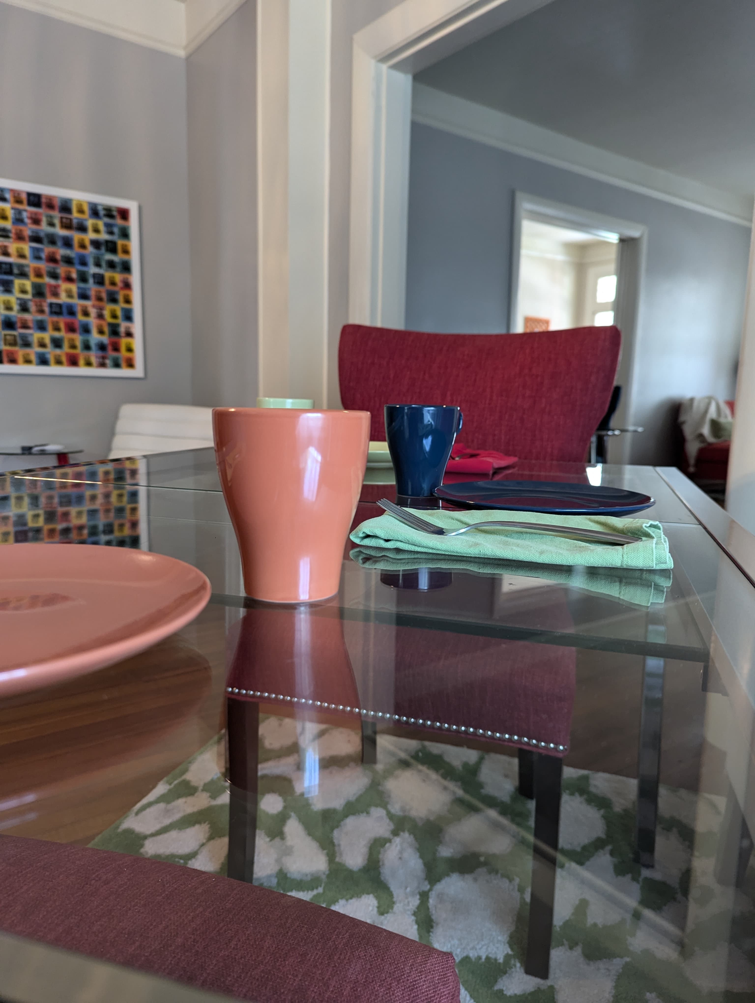 A colorful dining setup featuring plates, cups, and napkins on a glass table.