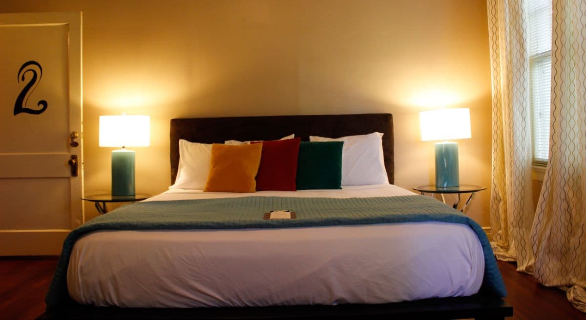 Cozy bedroom featuring a bed with colorful pillows, lamps, and a door marked with the number 2.