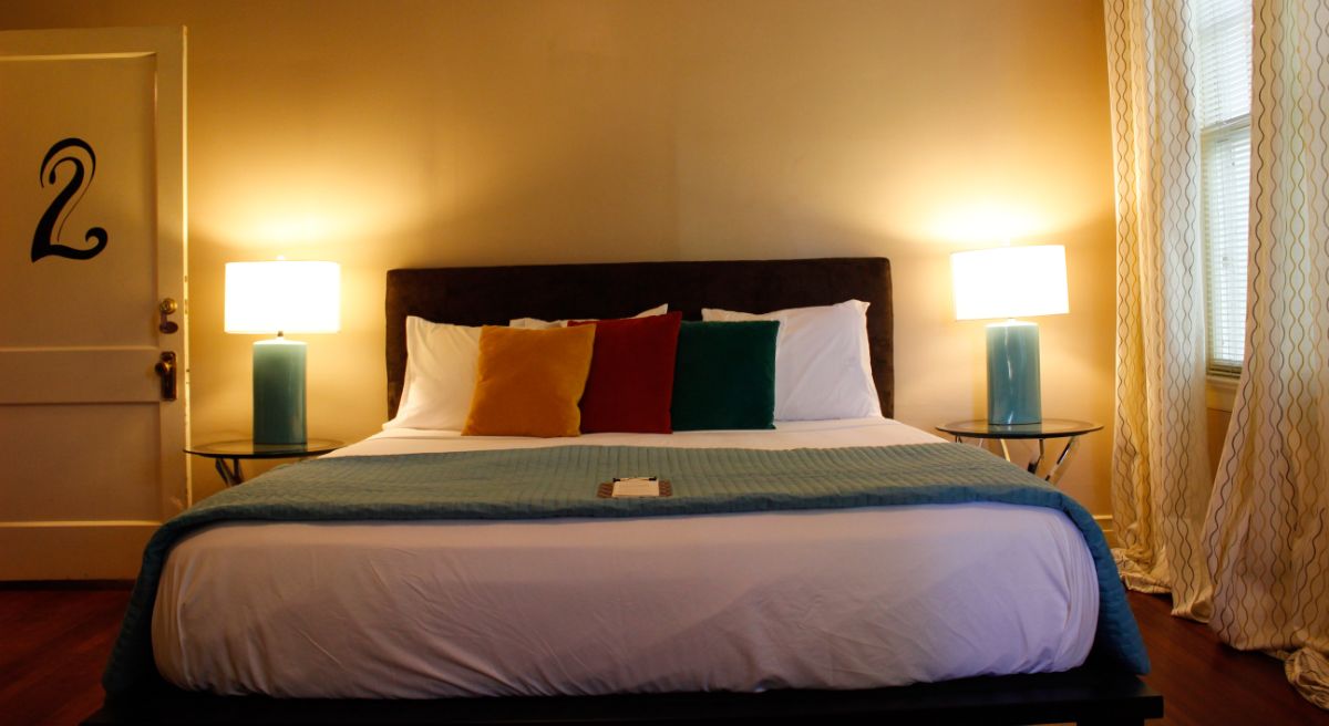 Cozy bedroom featuring a bed with colorful pillows, lamps, and a door marked with the number 2.